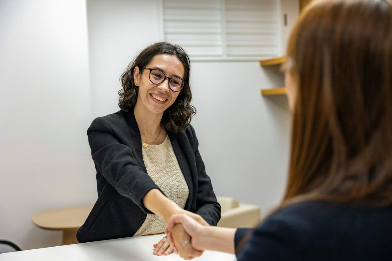 Two people shaking hands across a table after an interview